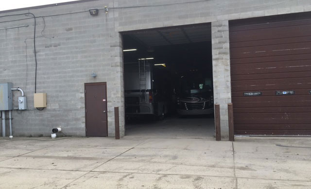 The image shows a garage with a large open door, and there are vehicles parked inside.