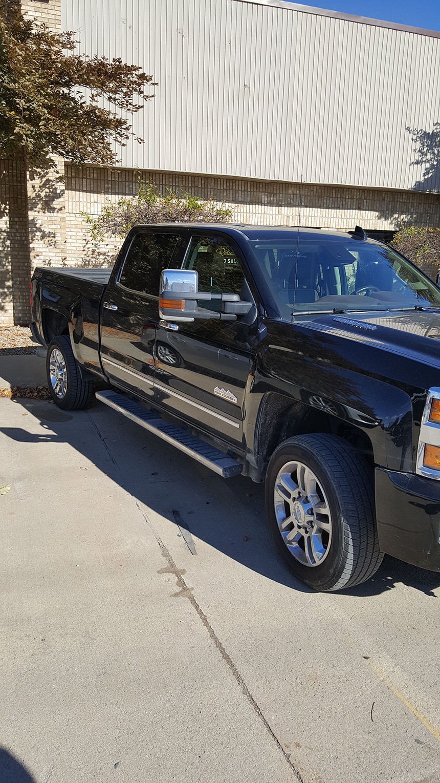 A black pickup truck parked next to a building with a white roof.
