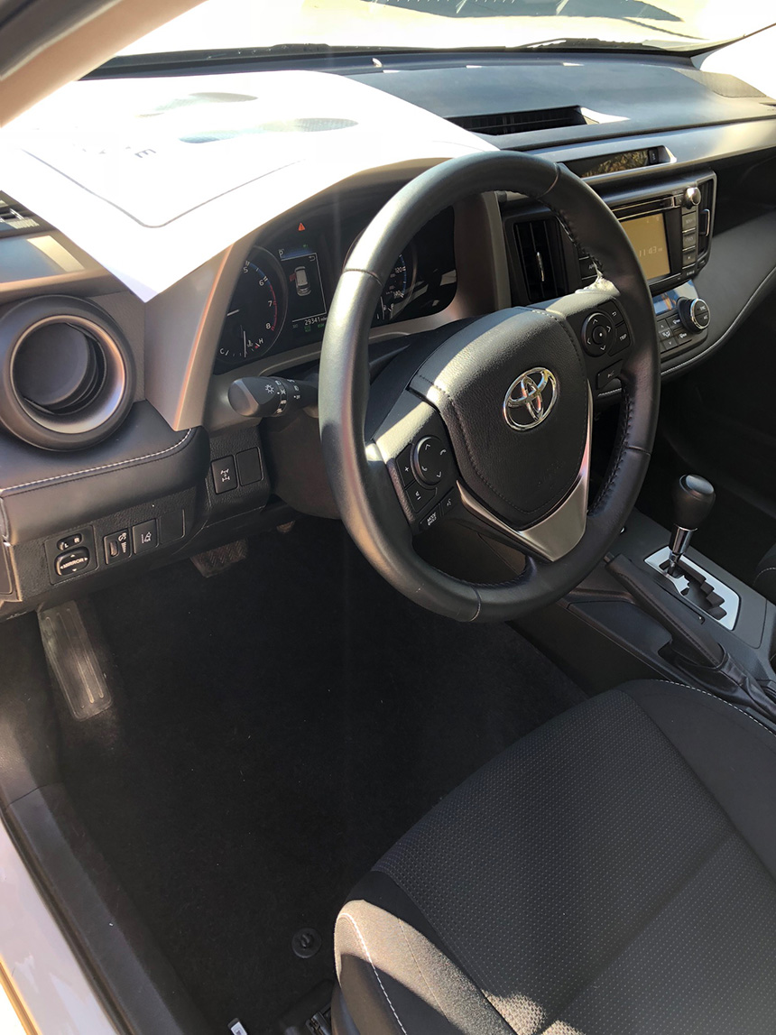 The interior view of a car s cabin, featuring a steering wheel, instrument cluster, and driver s seat.